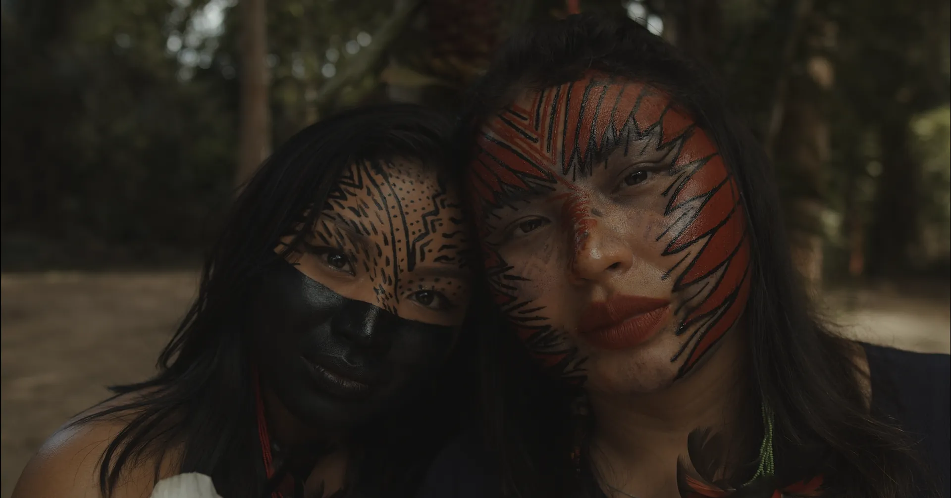 Two women with traditional face paint, cheek to cheek